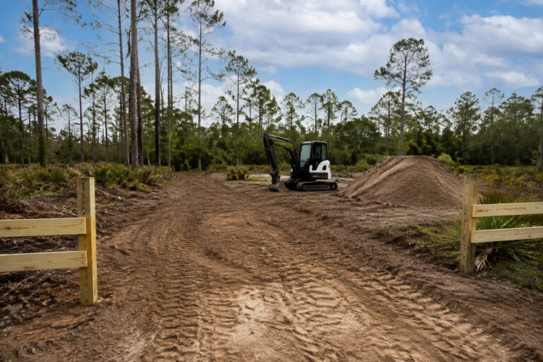 Excavator, graded soil, staging pile, and property access route in Florida