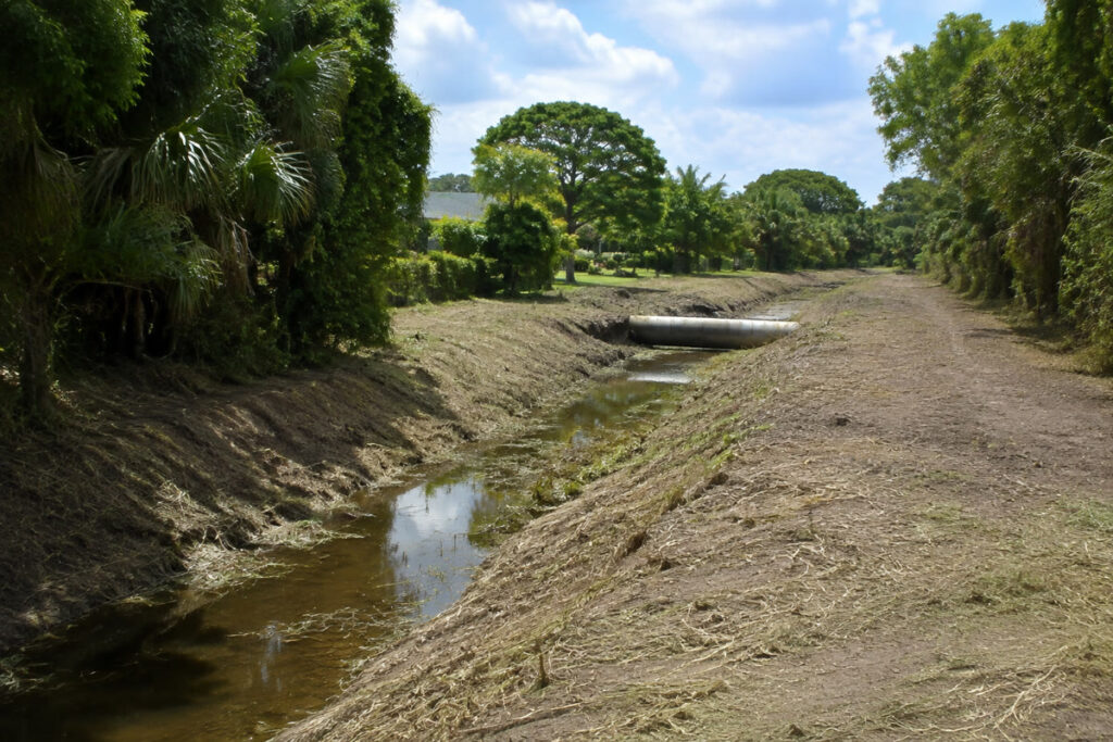 Cleared Florida drainage ditch with visible channel, culvert, and access corridor