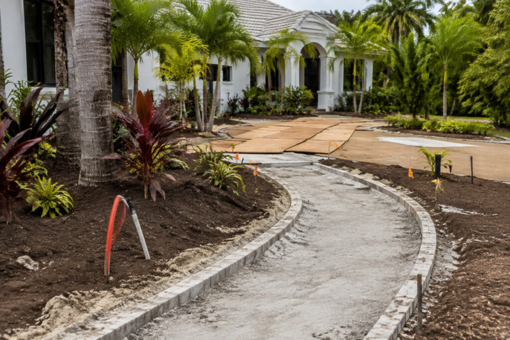 Unfinished walkway base, planting beds, and irrigation sleeves at a Florida home