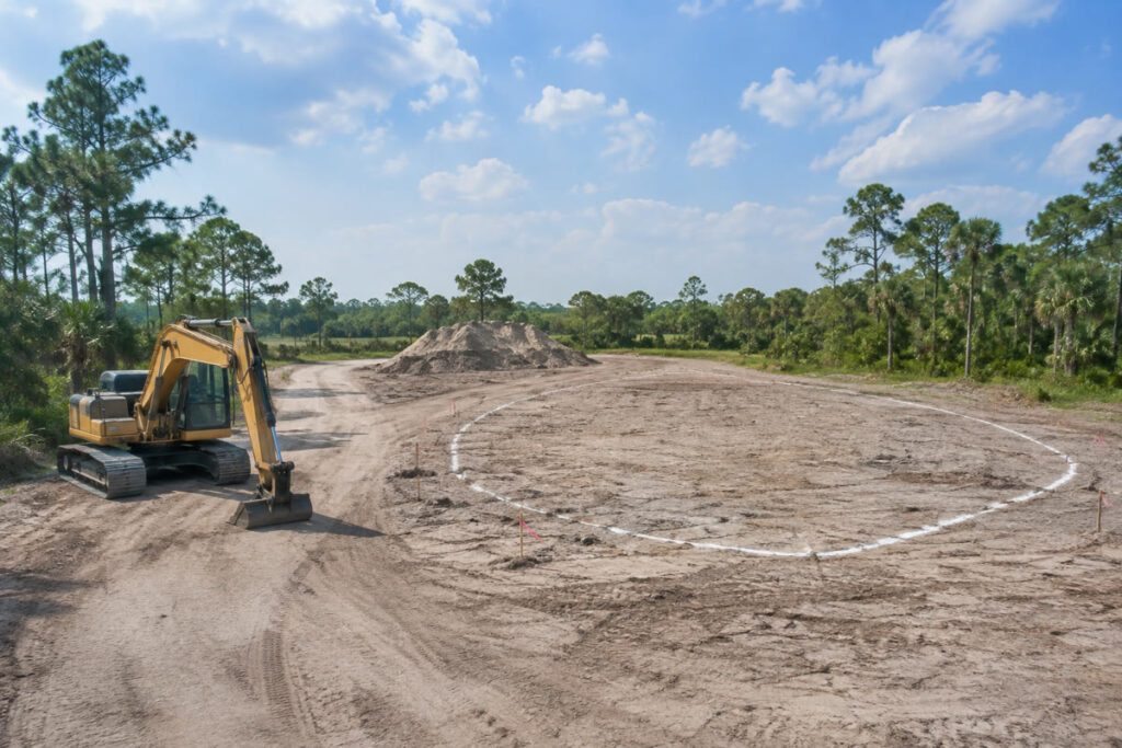 Marked pond construction footprint with excavator and soil staging on Florida acreage