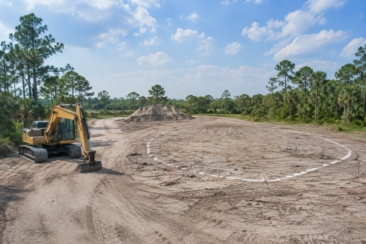 Marked pond construction footprint with excavator and soil staging on Florida acreage
